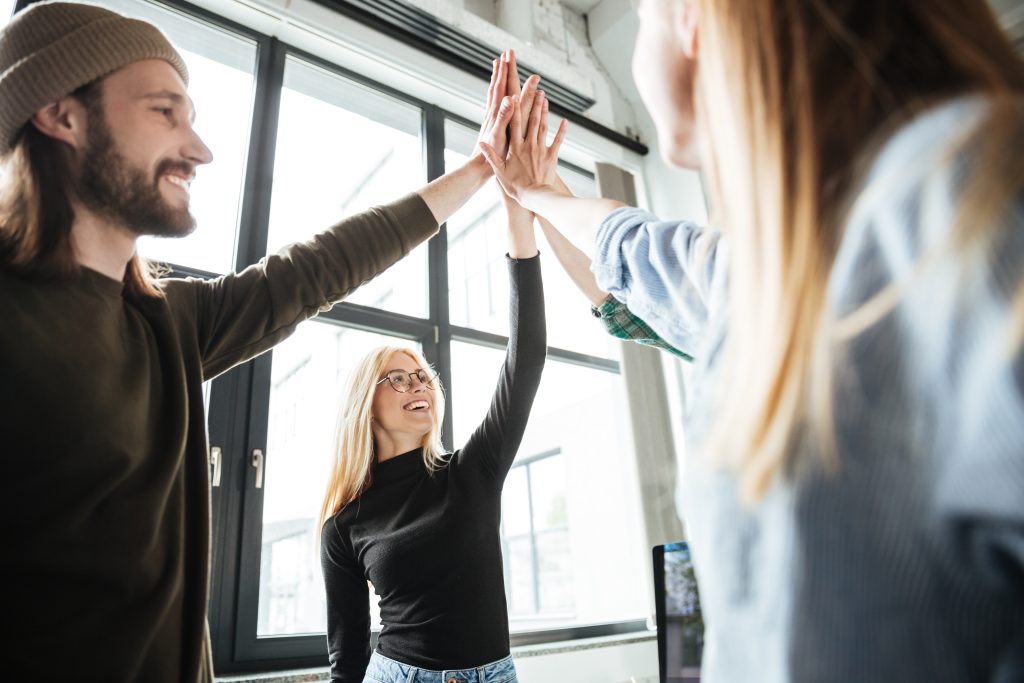 happy colleagues in office give high five to each other